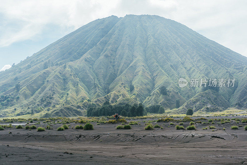 日出时分，一对夫妇在布罗莫火山附近驾驶摩托车