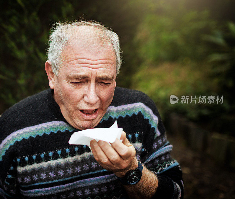 一位患感冒或流感的长者在自家花园里打了个喷嚏