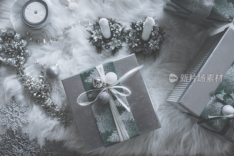 银色的圣诞装饰品和礼物排列在假毛皮地毯上