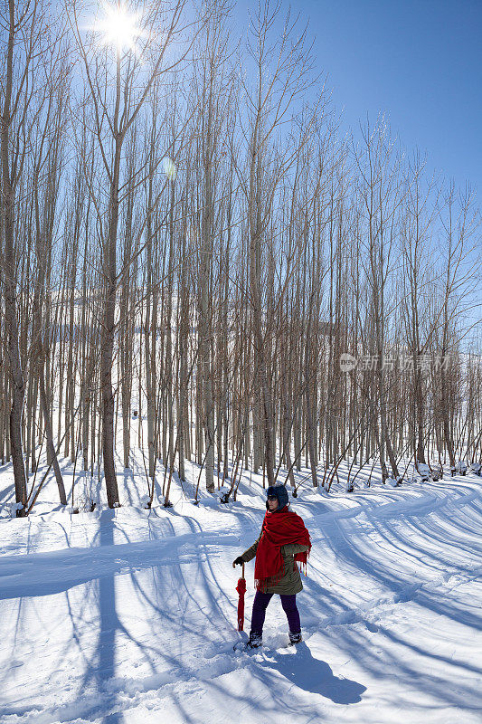 成年妇女穿着暖和的衣服在雪地上行走在农村