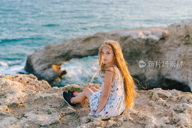 坐在塞浦路斯海边悬崖上的女孩