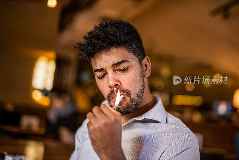 中年男子在酒吧里抽烟。