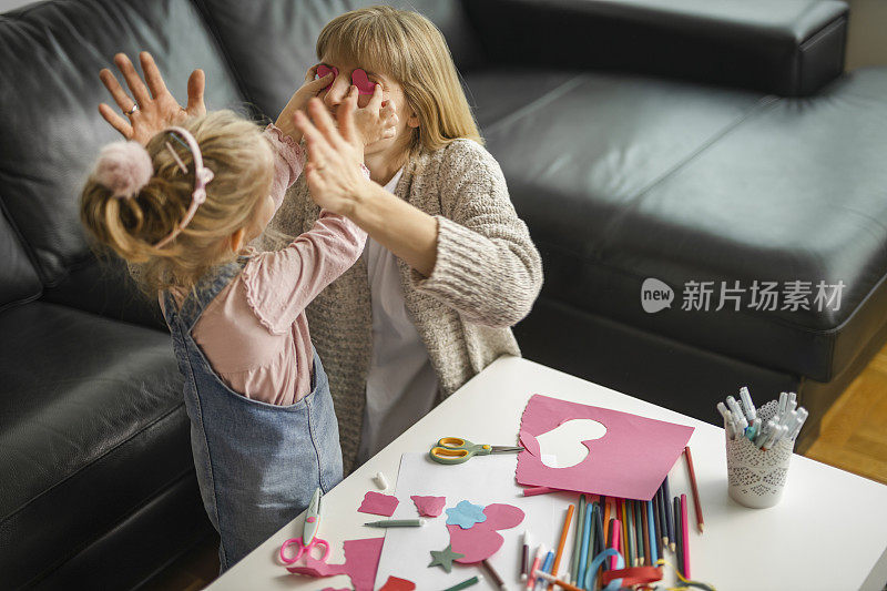 妈妈和女儿玩和有一个有趣的彩色纸