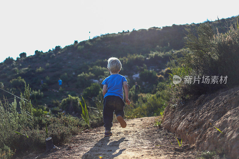 一个小男孩在山里的单行道上跑步