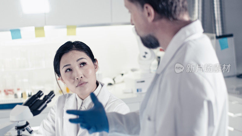 未来实验室。亚洲女医生使用显微镜，前景广阔