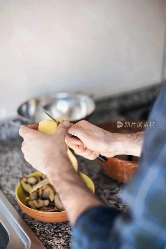 隔离烹饪:一名男子在煮土豆之前剥土豆皮