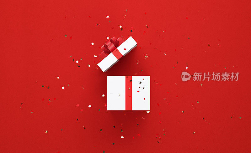 星星形状的五彩纸屑落在打开的白色礼盒与红丝带