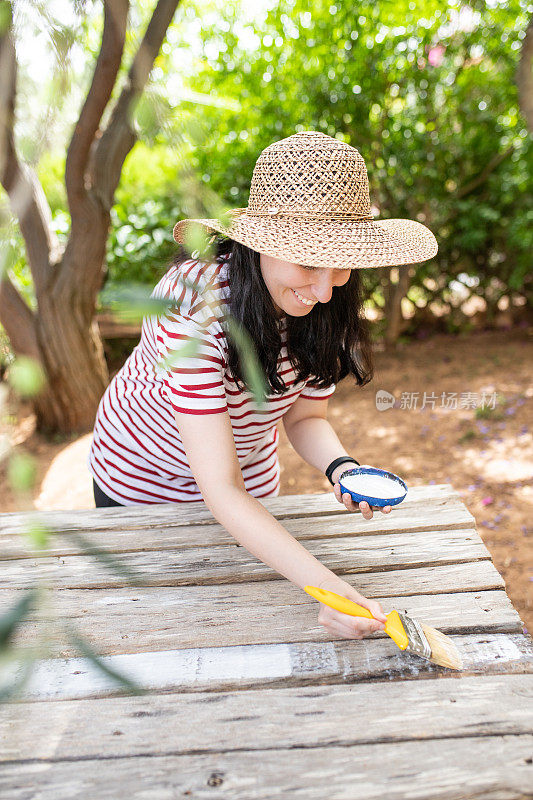 在花园里自己动手画木桌的女人