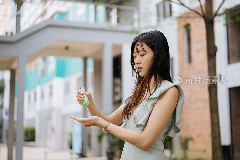 年轻的亚洲妇女用酒精洗手液消毒手