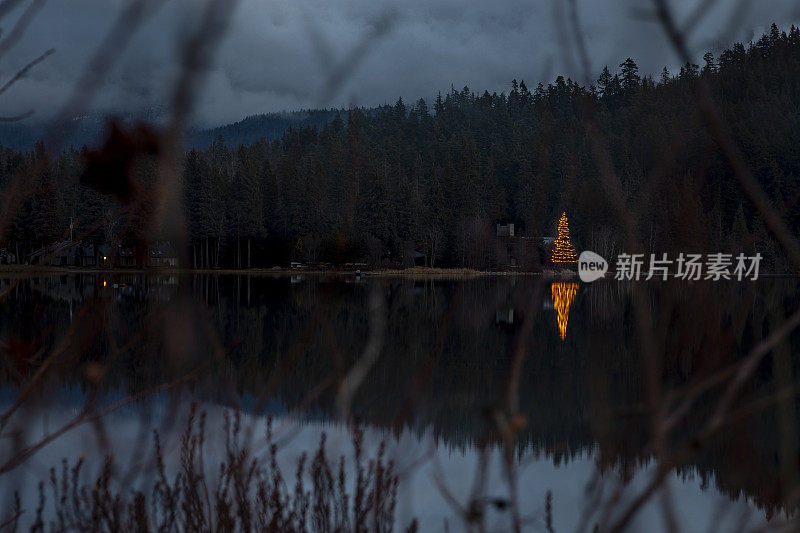 圣诞树灯倒映在湖与山景。