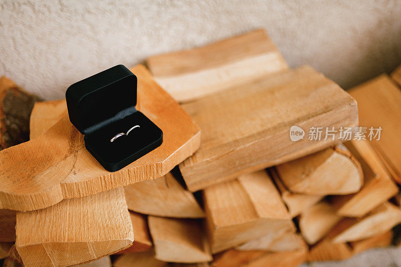 金色的结婚戒指放在黑色的天鹅绒盒子里，放在碎木头上。