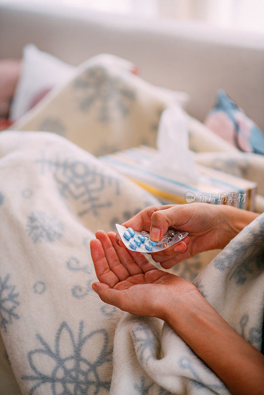 生病的女人用手拿着药丸