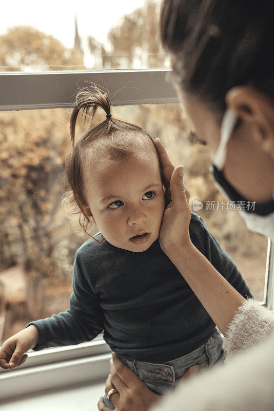 戴着防护面具的妈妈正在和女儿玩