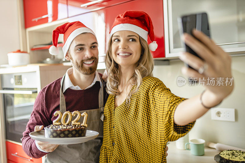 相爱的情侣用巧克力蛋糕自拍，在家里玩，庆祝新年;夫妇与朋友视频电话过年