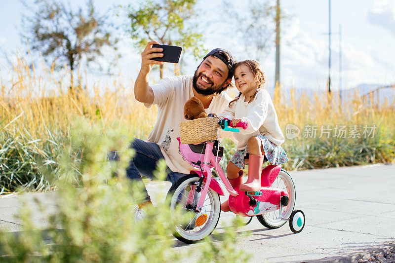 快乐的家庭，父亲教女儿在公园里骑自行车