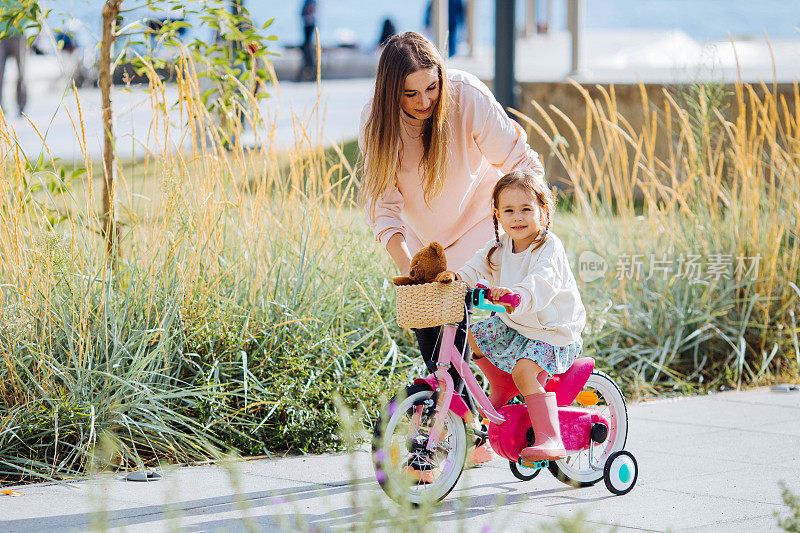 幸福的家庭妈妈教孩子女儿在公园里骑自行车