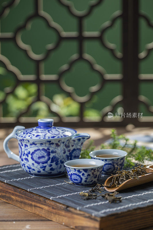 窗花旁桌上的青花瓷中国茶壶和茶杯富有禅意