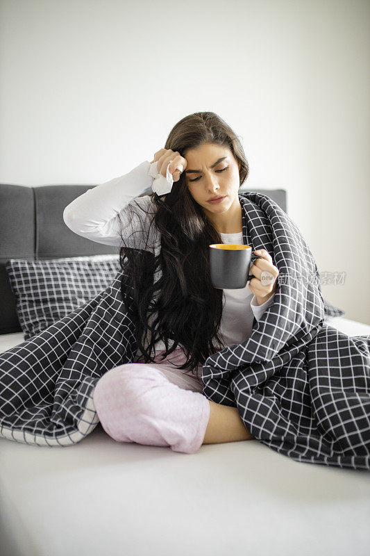 睡着的生病的小女孩躺在床上，感冒和高烧，喝着茶