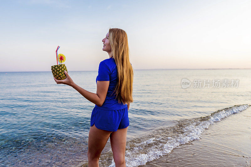 沙滩上喝着菠萝鸡尾酒的女人