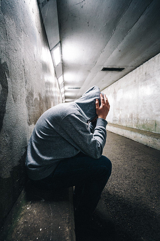 无家可归的抑郁的男人坐在地铁隧道里