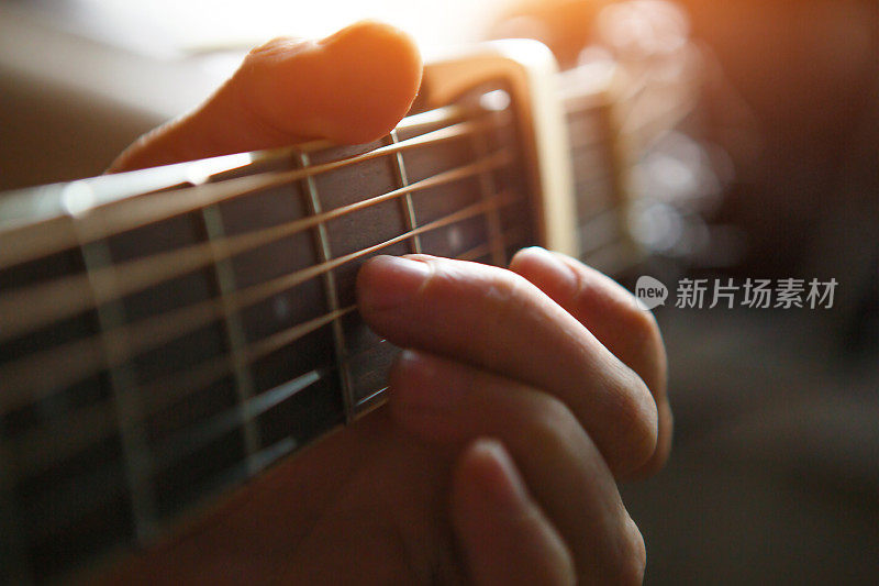 一个人的手放在吉他的指板上，手指穿过琴弦，夹住和弦。器乐，吉他课上的乐谱