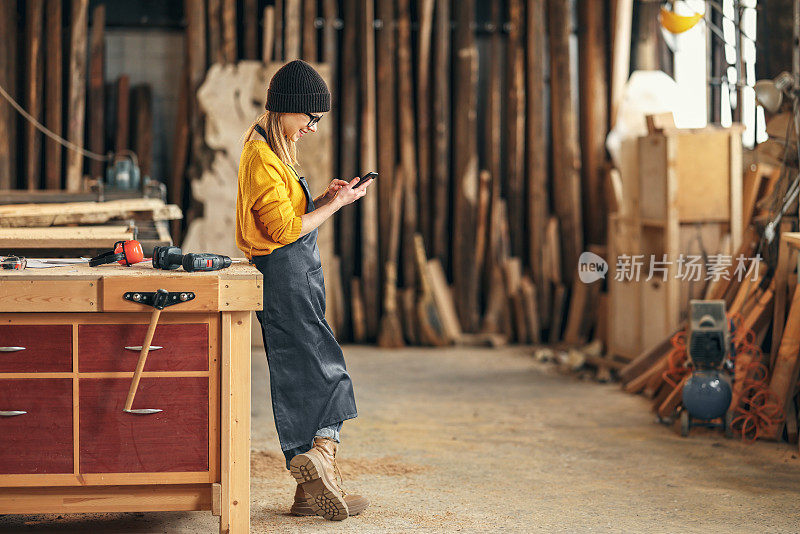 女木工在车间使用智能手机