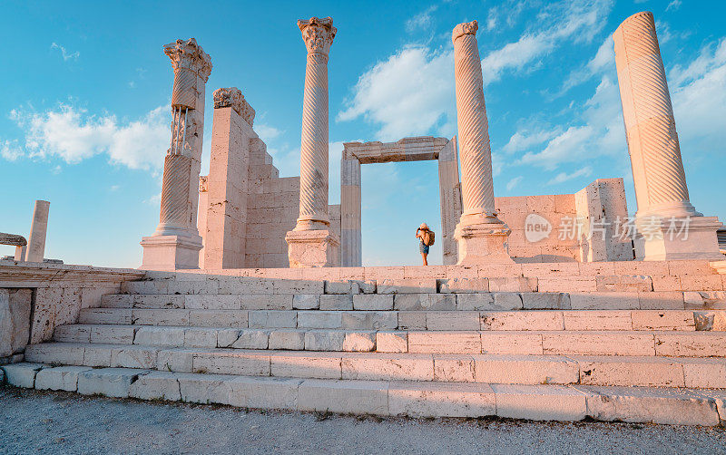 旅行者旅行者摄影师女孩在黄昏时在吕库斯老底嘉古城遗址的老底嘉教堂拍照