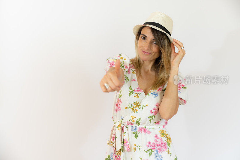年轻快乐开朗的女人戴着草帽，竖起大拇指孤立在白色的背景上。