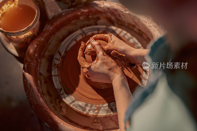 女大师在工作室的陶轮上塑造粘土