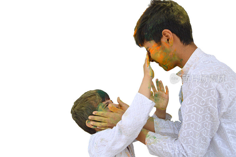 两个快乐的小男孩在白色的库尔塔应用gulaal在对方的脸颊上，印度教节日胡里节-脸，手，头发和衣服涂上彩色的粉末颜色-孤立在白色的背景