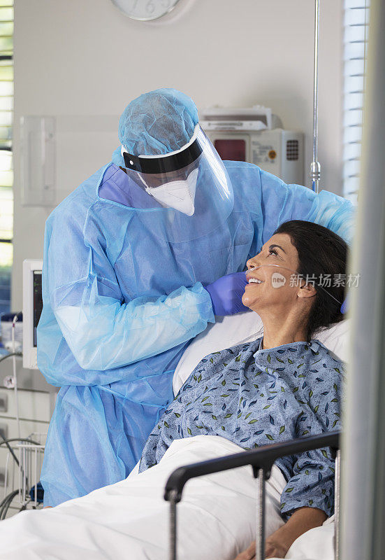 穿着PPE的男护士调整女病人的氧气管