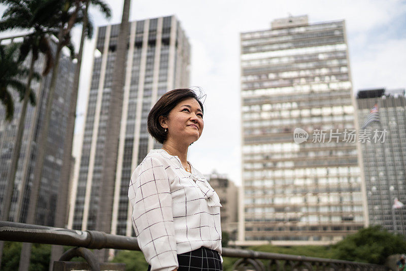 沉思成熟的亚洲女商人，在城市中望向别处
