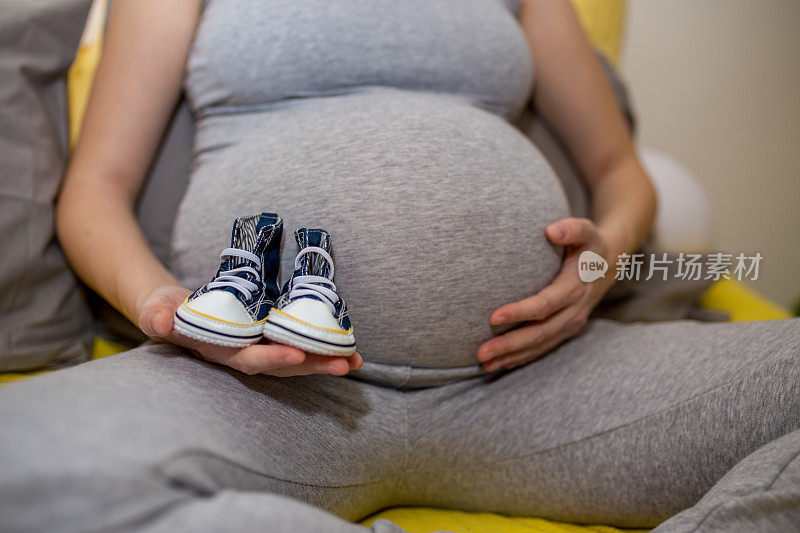 孕妇拿着小鞋子靠近肚子