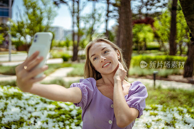 美丽的女人使用手机在大自然和拍照