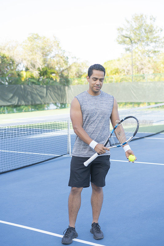 男子网球运动员的肖像与球拍和球在网球场网附近