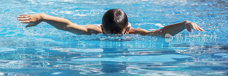 男孩儿童游泳运动员在游泳池里蝶泳。水上运动、训练、比赛、活动，为孩子们上学游泳班。宽横幅