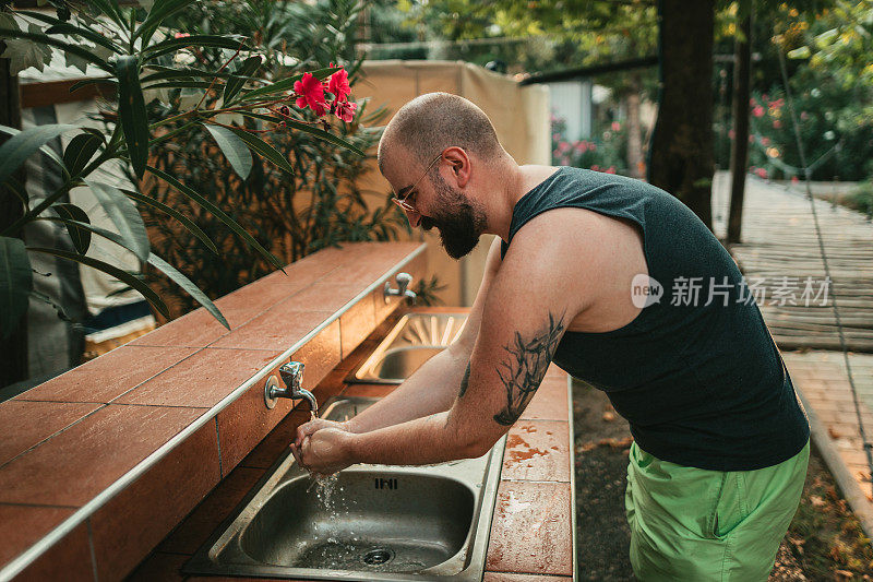 一名男子在度假营地的水池边洗手