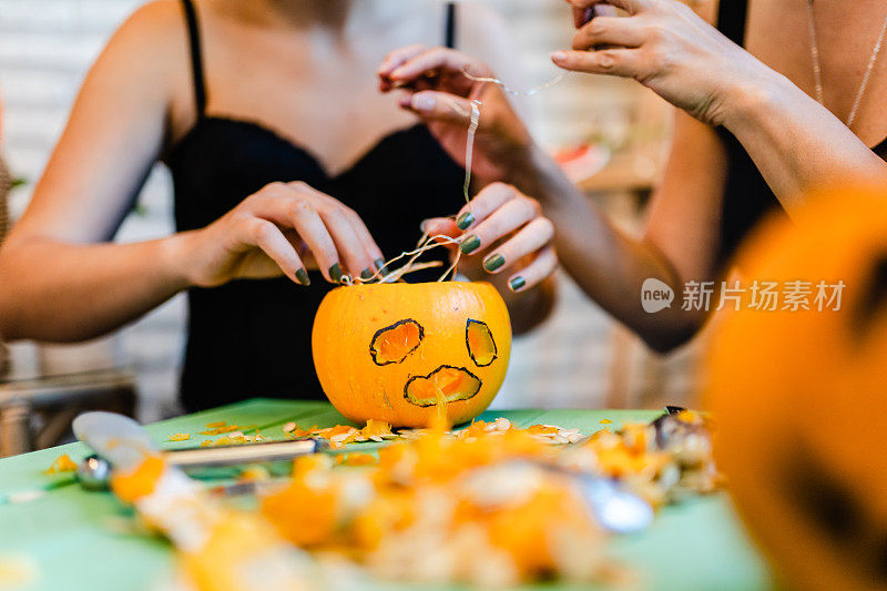 两个朋友在家里庆祝万圣节，雕刻南瓜