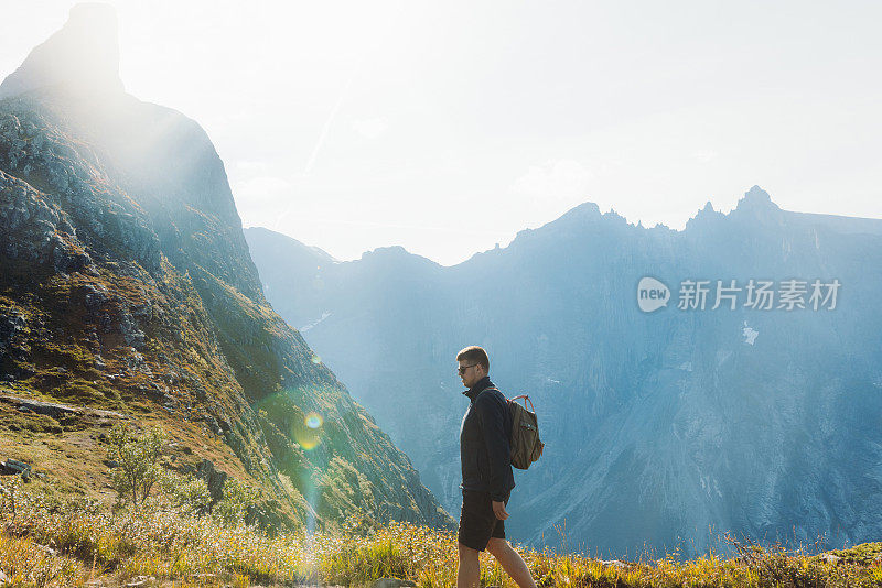 在阳光明媚的秋日，一个背着背包的人在挪威的山上徒步旅行