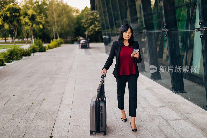 商务女性拖着她的个人行李的完整长度的观点