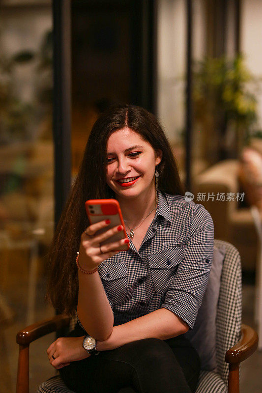 年轻美丽快乐的女人在咖啡馆用手机检查手机银行交易