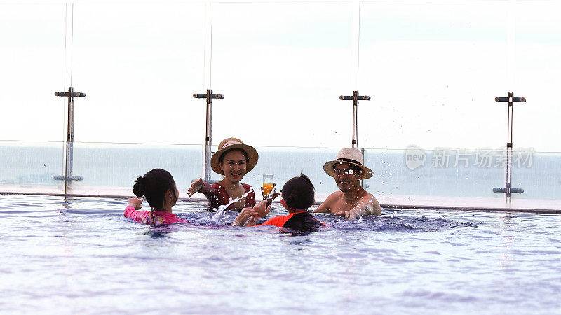 欢快快乐的父母和孩子一起在游泳池里玩耍，快乐的家庭在游泳池里度过暑假