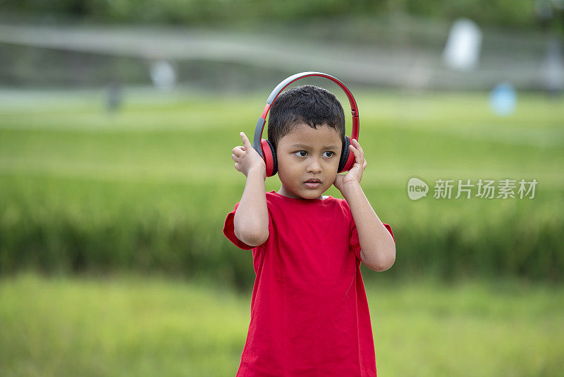 蹒跚学步的男孩用耳机听音乐