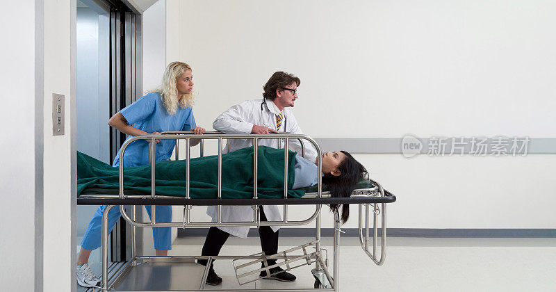 护士和护理人员把病床从电梯里推到医院的急诊室。