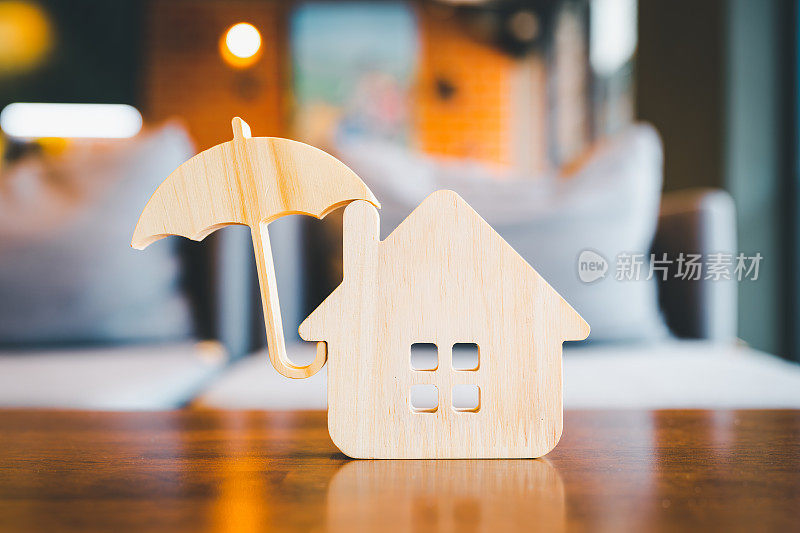 木屋模型和不动产保险构思，个人手持小雨伞和样板房。房屋灭失和火灾保险，建筑火灾保险概念。