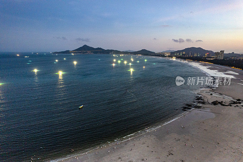 夜间在海岸线上捕鱼的船只被灯光照亮