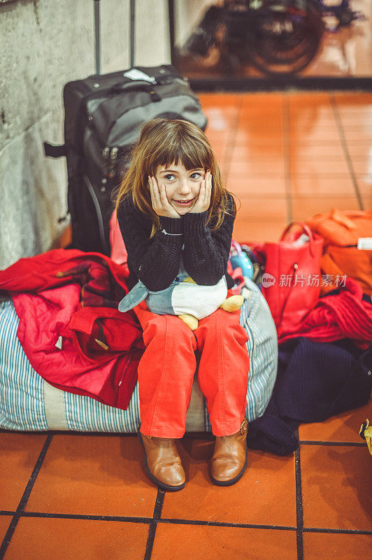 疲惫的年轻女孩在机场带着行李等待家人的旅行延误
