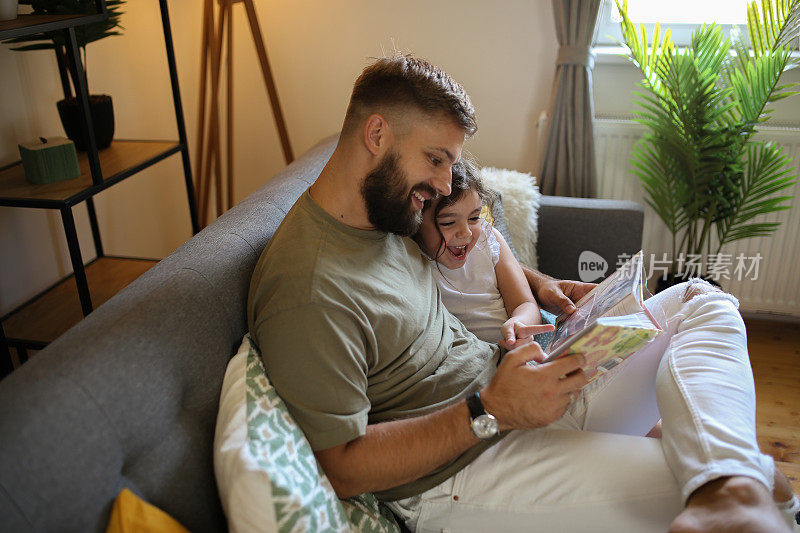 父亲和女儿在新家搬家时看着相册。库存图片