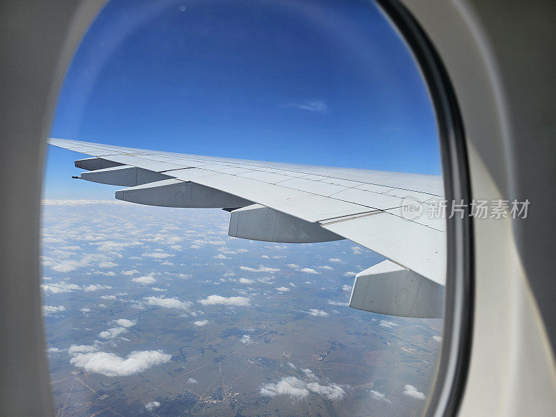 透过窗户看飞机飞行期间在机翼与一个漂亮的蓝天概念