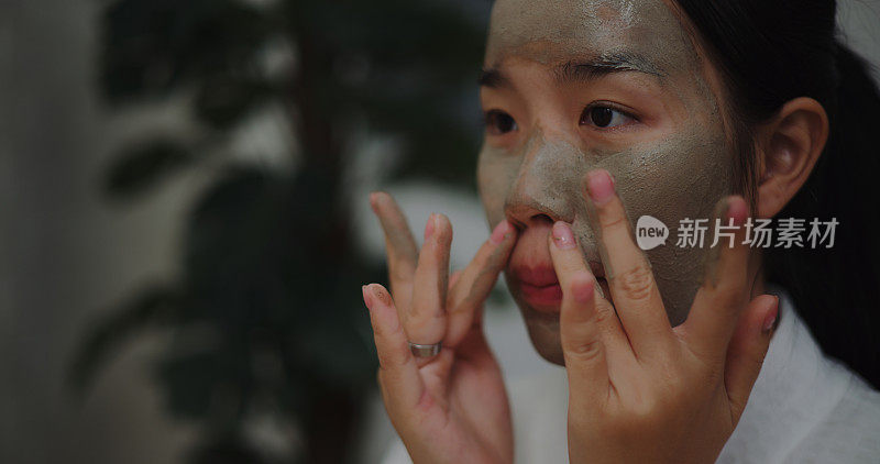 穿着浴袍的年轻亚洲女子在敷面膜美容脸